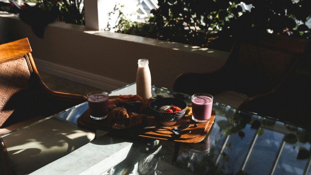 Warm morning breakfast with croissants, fruit, and smoothies on a balcony table. Ideal for lifestyle themes.